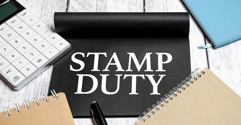 Stamp Duty written on a mouse mat with notepads and calculators surrounding it.