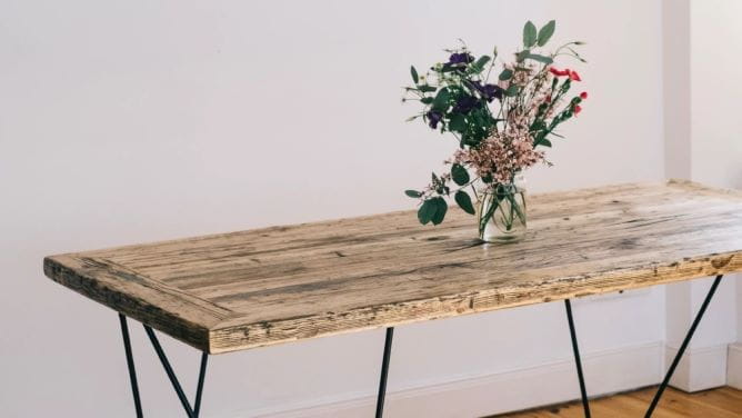 wooden table in a white room with a vase of flowers on