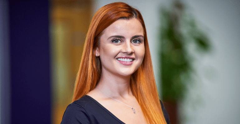 Young professional woman with long red hair smiling.