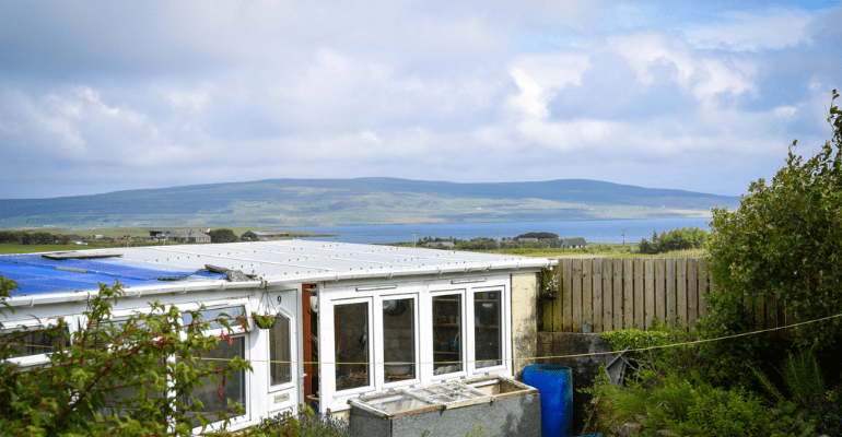 A white shed in front of stunning coastal view.