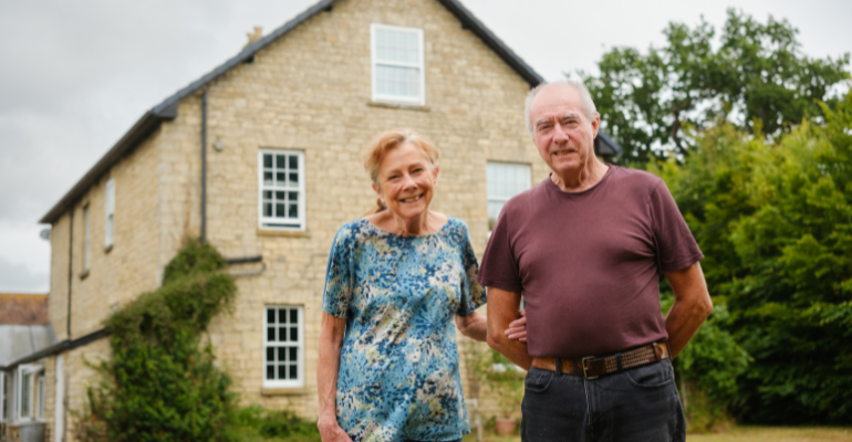Retired couple, Jane and Tony Ryan, standing outside their renovated farmhouse.