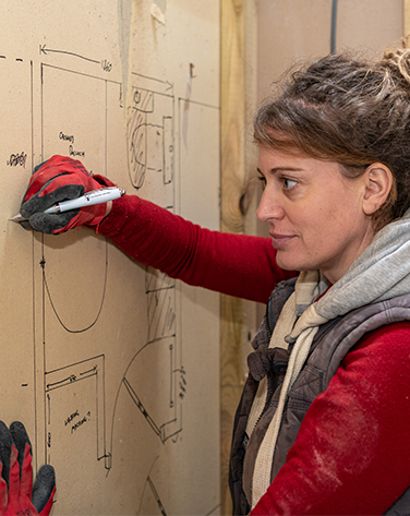 Female drawing renovation plans on wall.
