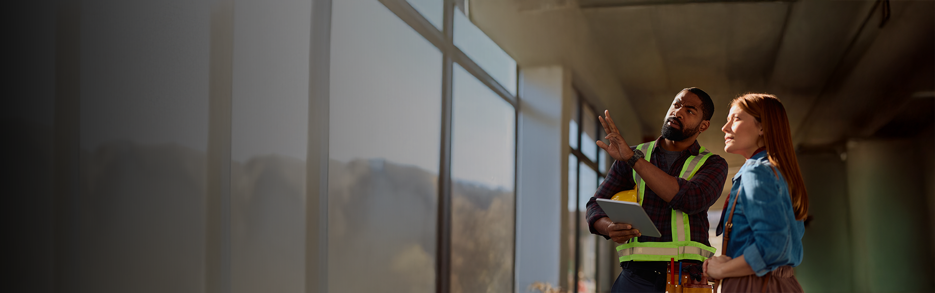 A construction contractor talking to a client in an unfinished building.