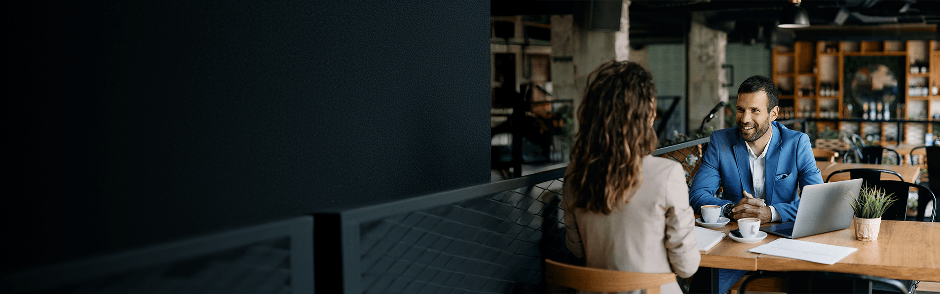 A man and a woman at a café discussing business.