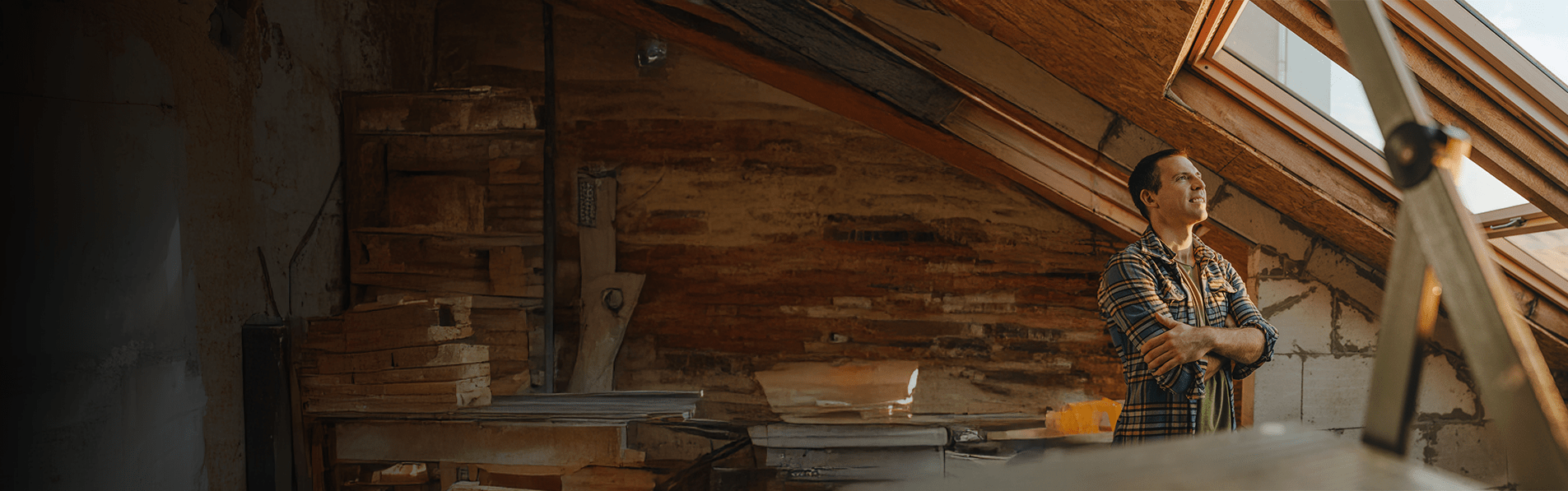 A man smiling looking out of a sky window in a loft.