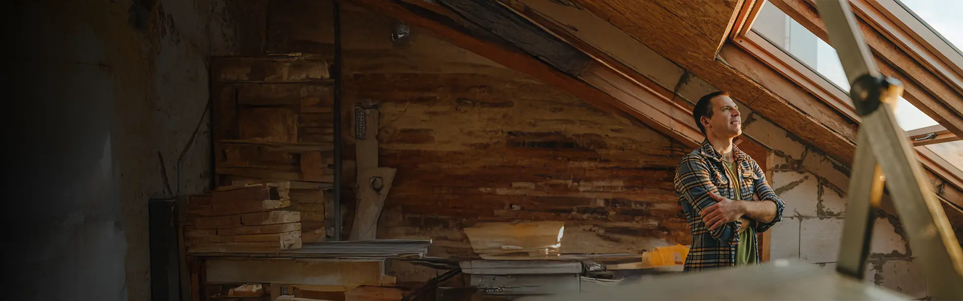 A man smiling looking out of a sky window in a loft.