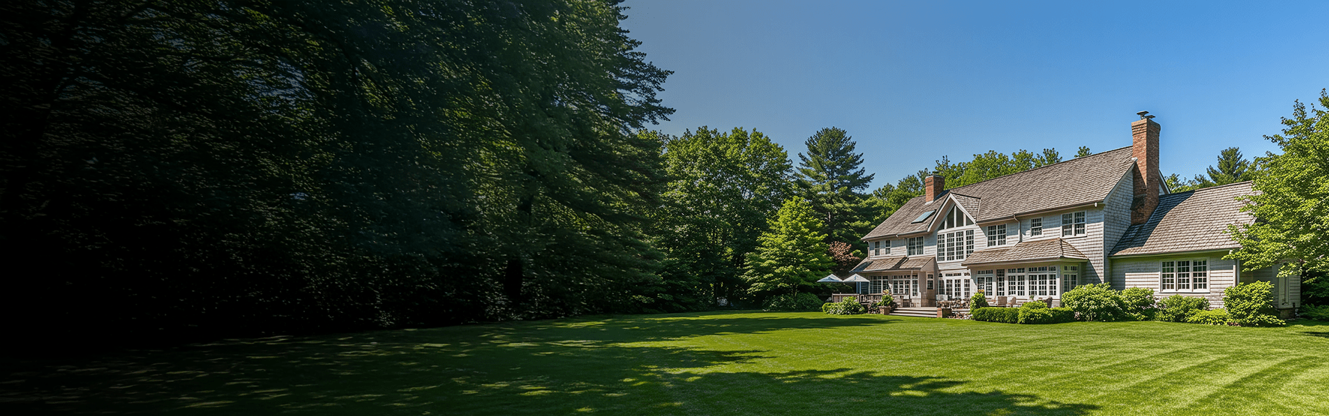 A wide shot of a large modern house with a sizable garden.