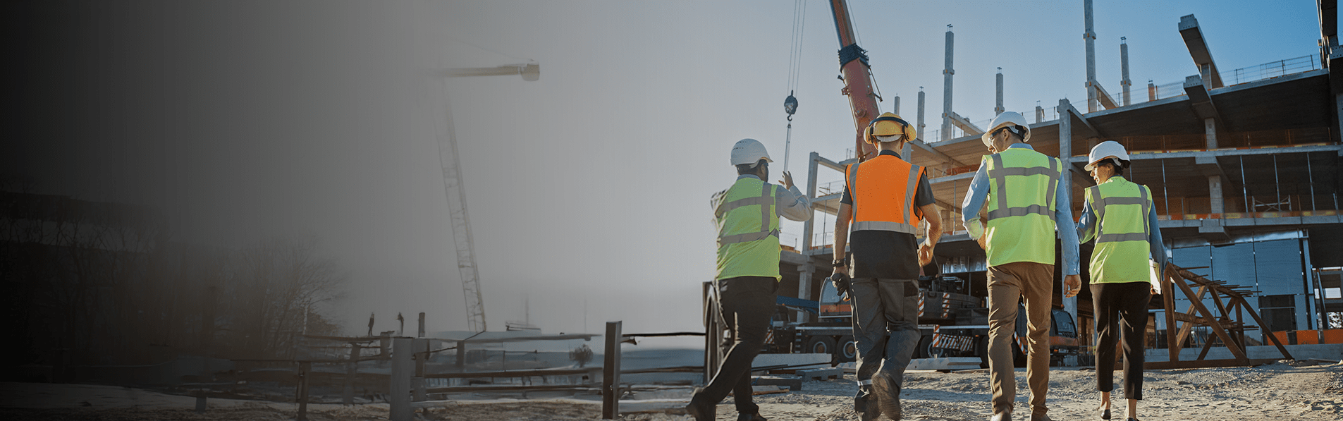 A wide shot of four people in high vis walking up to a construction site.