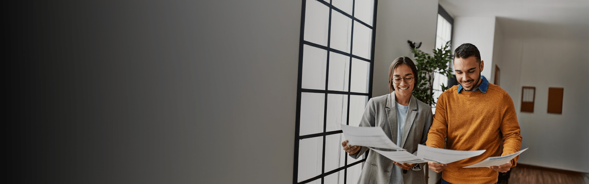 A woman and a man looking at documents together in a building.