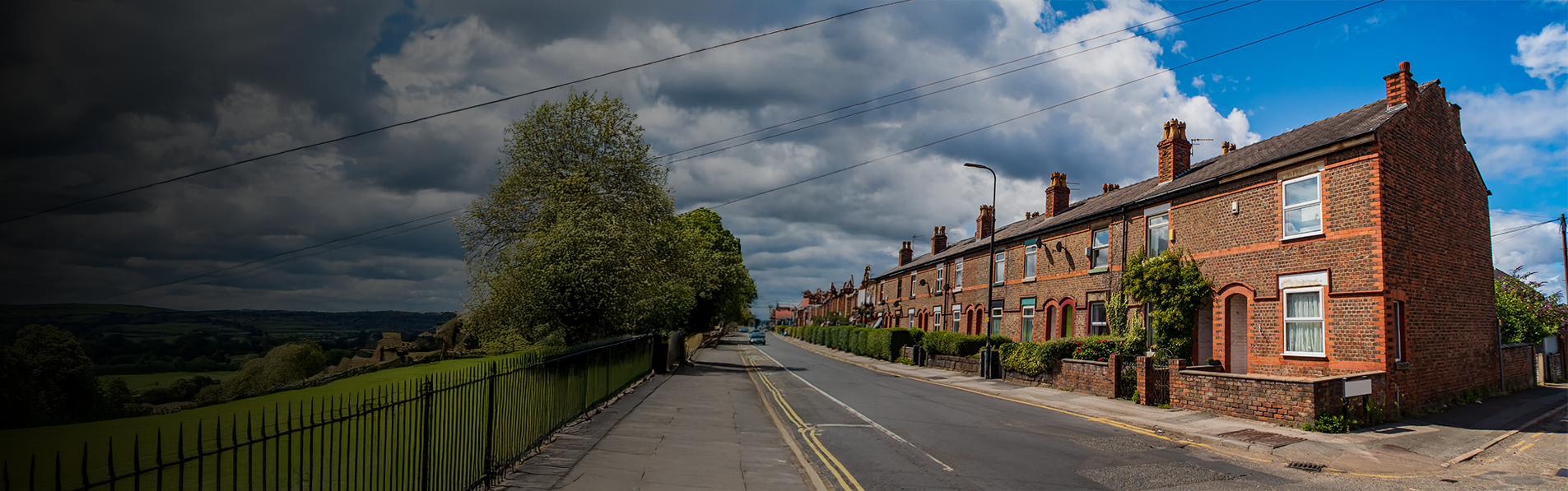 A street with a row of terraced houses opposite a field.