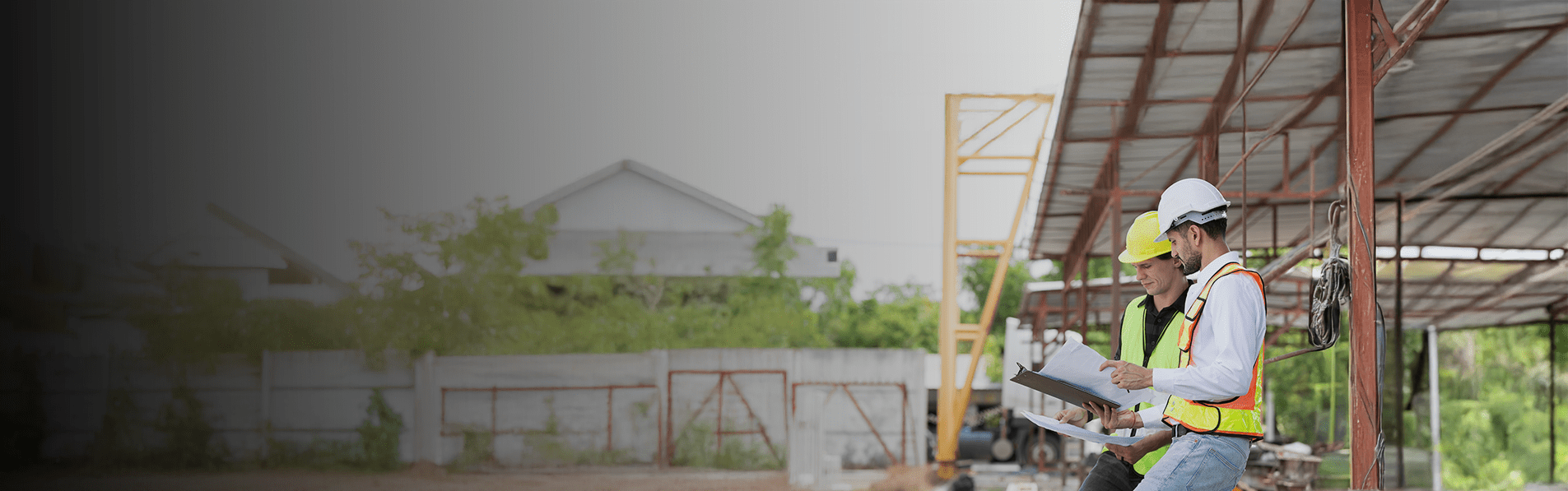 Two builders in high vis jackets looking through documents on a building sit.
