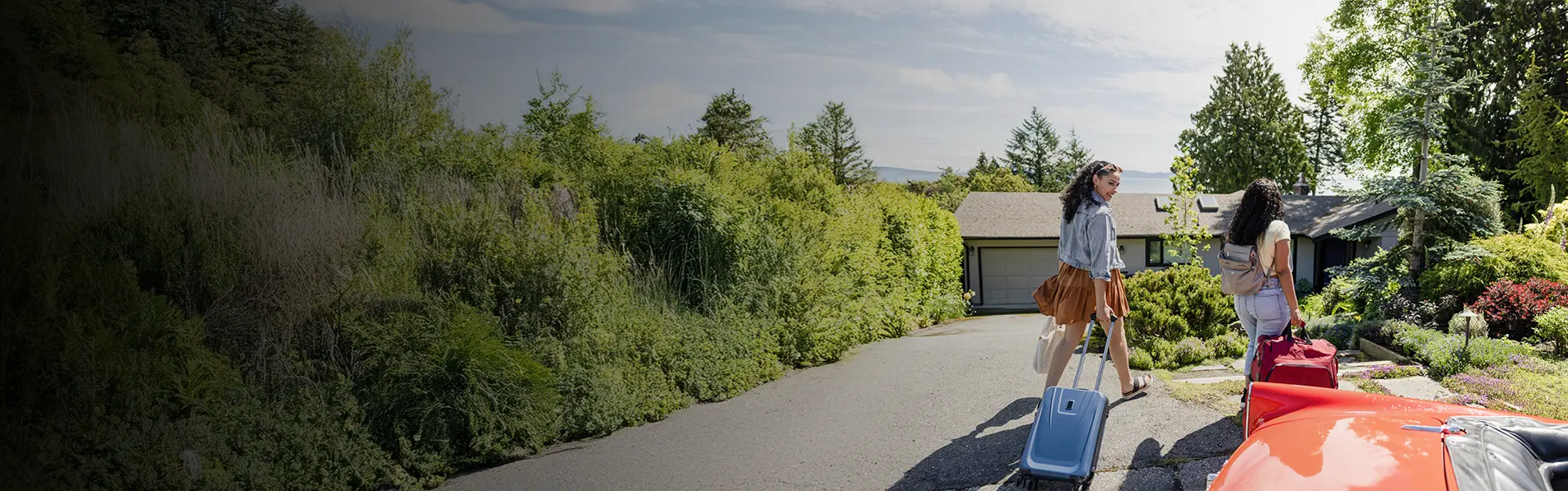 Two women with suitcases heading into a bungalow.