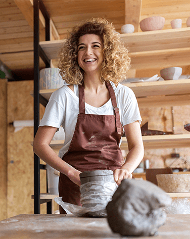 A lady smiling whilst create pottery.