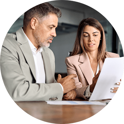 Man in a grey suit and woman in a pink suit looking at a shared document