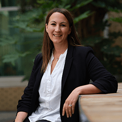 Julie Twynholm with long brown hair sat smiling.