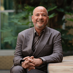 Marc Goldberg sat smiling wearing a grey suit.