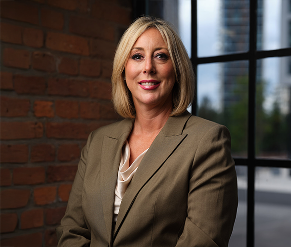 A woman with a short blonde bob smiling wearing a green suit smiling.