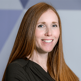 A woman with long ginger hair smiling wearing a black blouse.