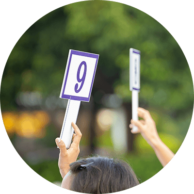 A close up of people holding auction panels up.
