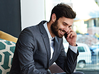 A close up of a salesman talking on a phone in a modern office.