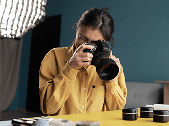 A woman with dark hair taking close up pictures on a desk.