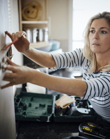 A woman wearing a stripy top measuring and marking wall