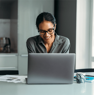 A close up of a professional woman working from home on a laptop in a modern kitchen.