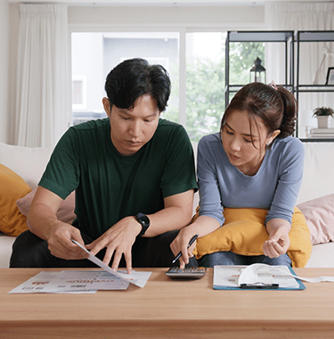 A couple sat together on a couch looking through documents.
