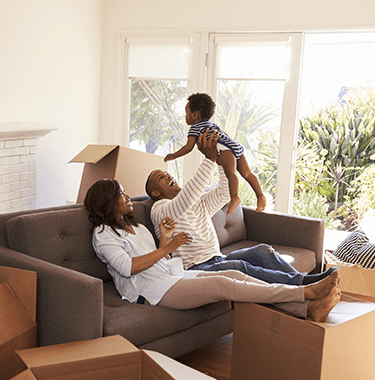 A family sat on a couch whilst playing with their child after moving in.