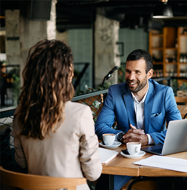 A man and a woman at a cafe discussing business.
