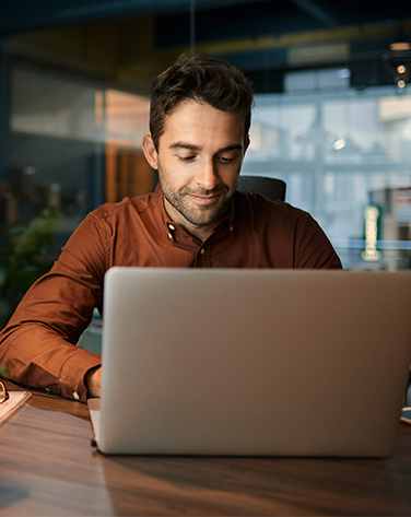 A man with short brown hair sat at a desk on his laptop.