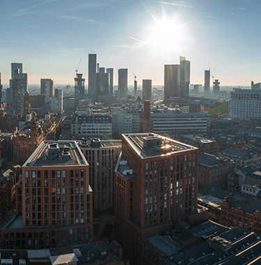 A wide shot of Manchester city centre with a sunrise.