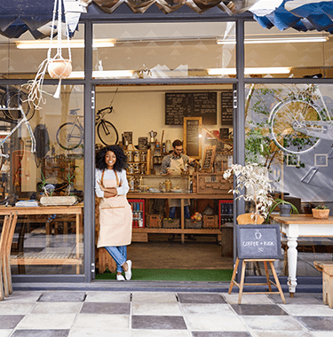 A woman leaning on the door of her cafe that also sells bikes.