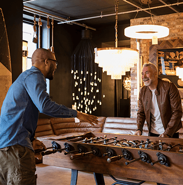 Two men laughing playing foosball.