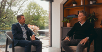 Two businessmen sitting casually in a beautiful office, smiling at the camera.