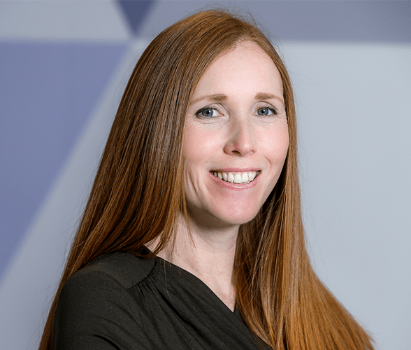 A woman with long ginger hair smiling wearing a black blouse.
